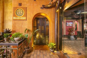 A traditional entrance with a wooden door, potted plants, and a sign reading "KECHO LEGACY".