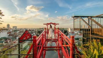 A red bridge leading to a glass-walled observation deck with a city view.