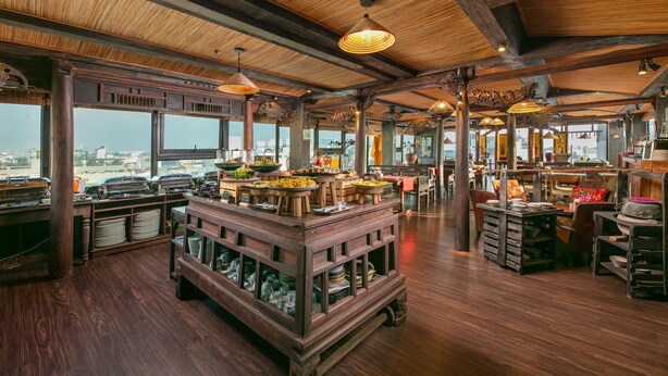 Un restaurante espacioso con techo alto, vigas de madera y mesas de buffet.
