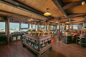 A spacious restaurant with a high ceiling, wooden beams, and a buffet setup.
