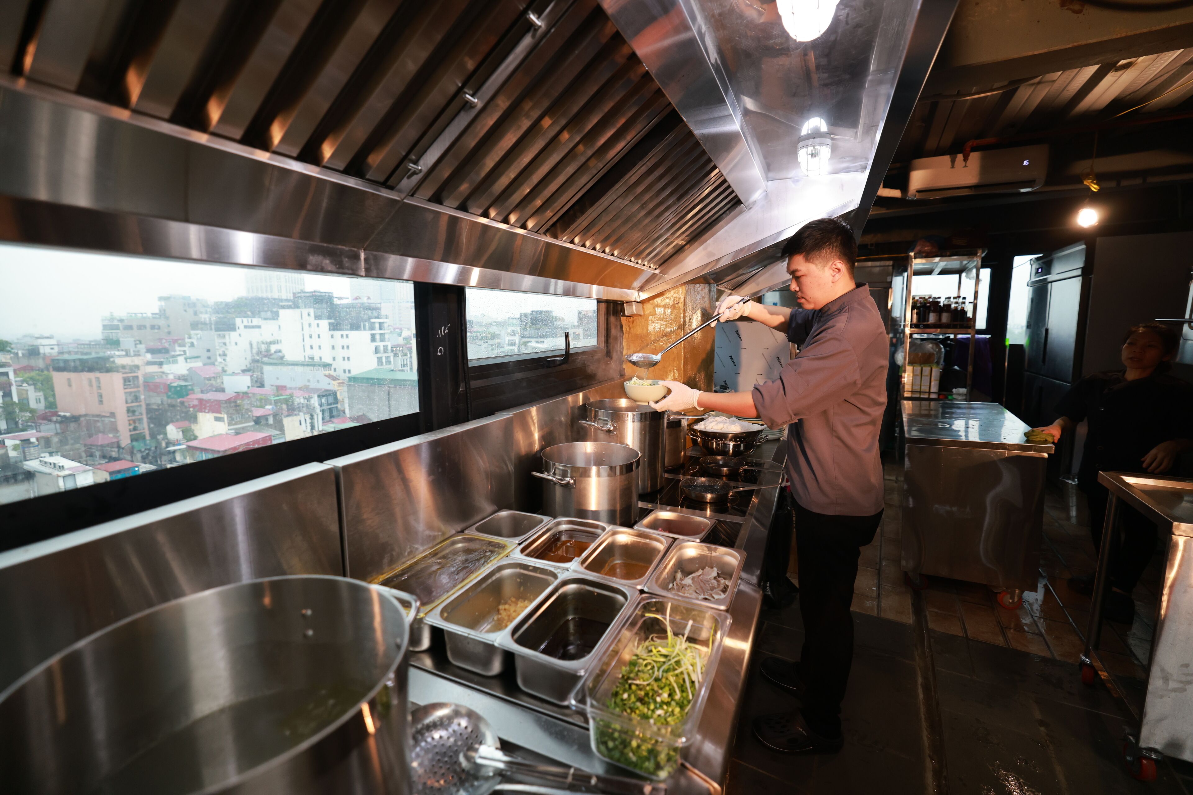 Une cuisine équipée d’appareils électroménagers en acier inoxydable et dotée d’une fenêtre donnant sur un paysage urbain.
