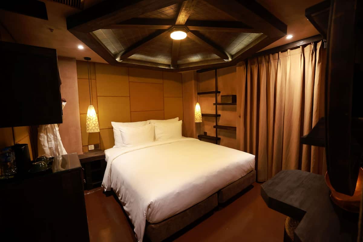 Une chambre d’hôtel avec un grand lit, des lampes de chevet, un téléviseur à écran plat et une tête de lit en bois.