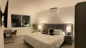 Quarto moderno com cama grande, abajures, escrivaninha e uma cadeira.