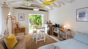 Una habitación acogedora con cama, una mesa de comedor, una zona de cocina y vistas a la vegetación.