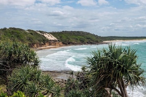 Un paysage côtier avec une plage, des vagues et une végétation luxuriante.