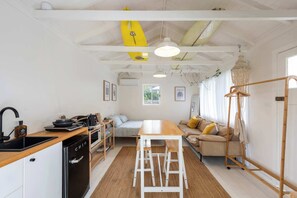Une cuisine compacte équipée d’un lave-vaisselle, d’un plan de travail en bois et d’un coin repas avec une table et des chaises.