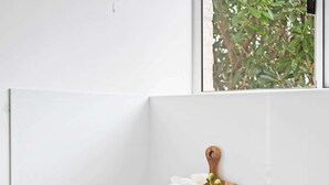 A laundry area with a Samsung washing machine, a wooden cutting board, a vase with white flowers, and a small bowl. - Chic 1-Bed Escape with Parking Bridgeman Downs (Bridgeman Downs)
