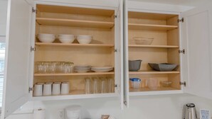 Un meuble de cuisine blanc, doté de plusieurs étagères, dont certaines contiennent des bols, des assiettes et des verres.