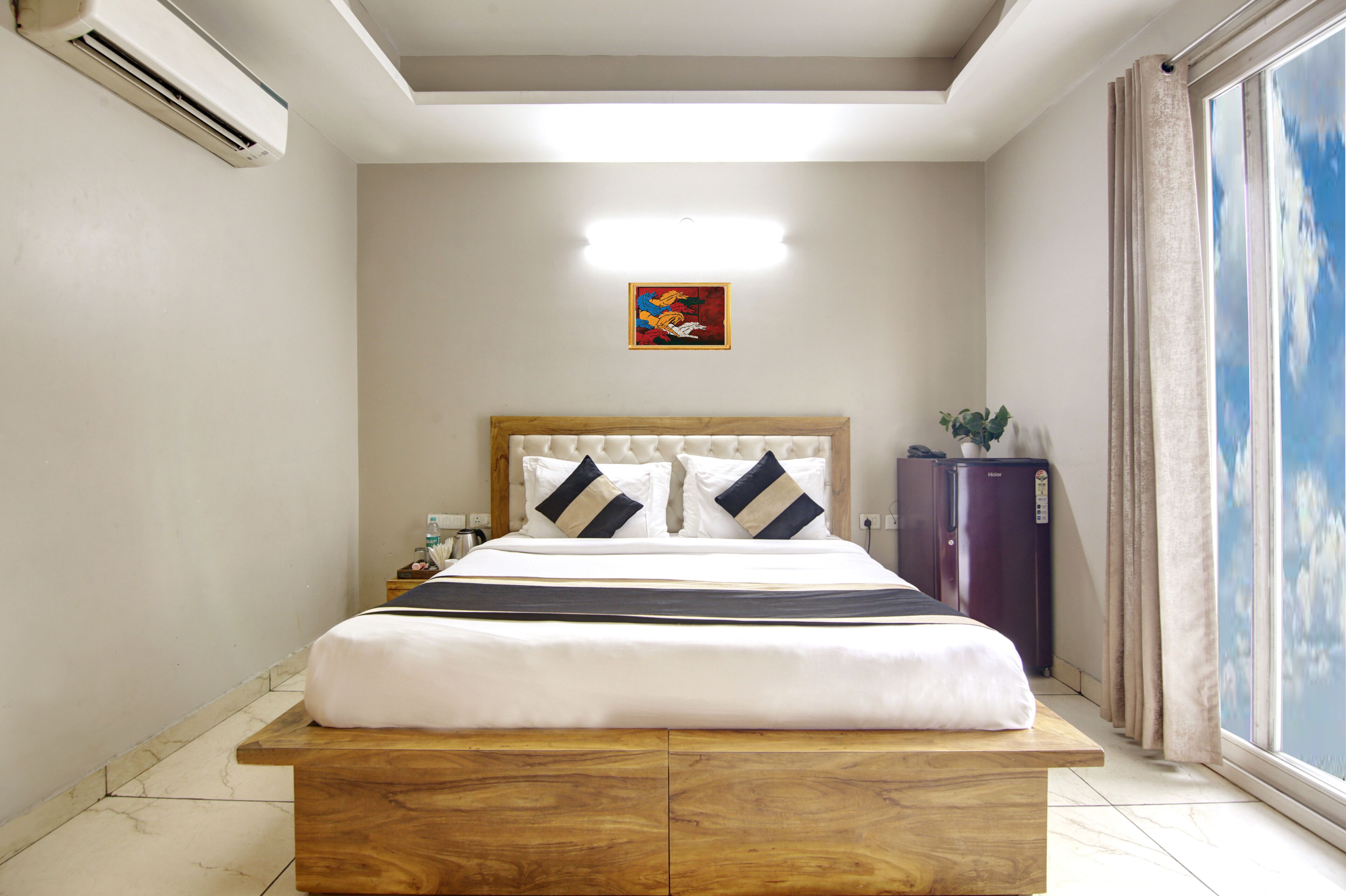 Habitación de hotel con cama, mesita de noche, cómoda y ventana con cortinas.
