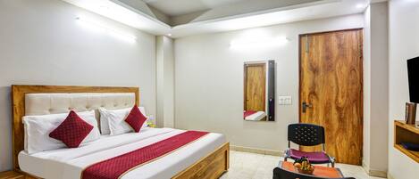 Quarto com cama de madeira, ventoinha no teto, guarda-roupa de madeira e uma pequena mesa com cadeira.