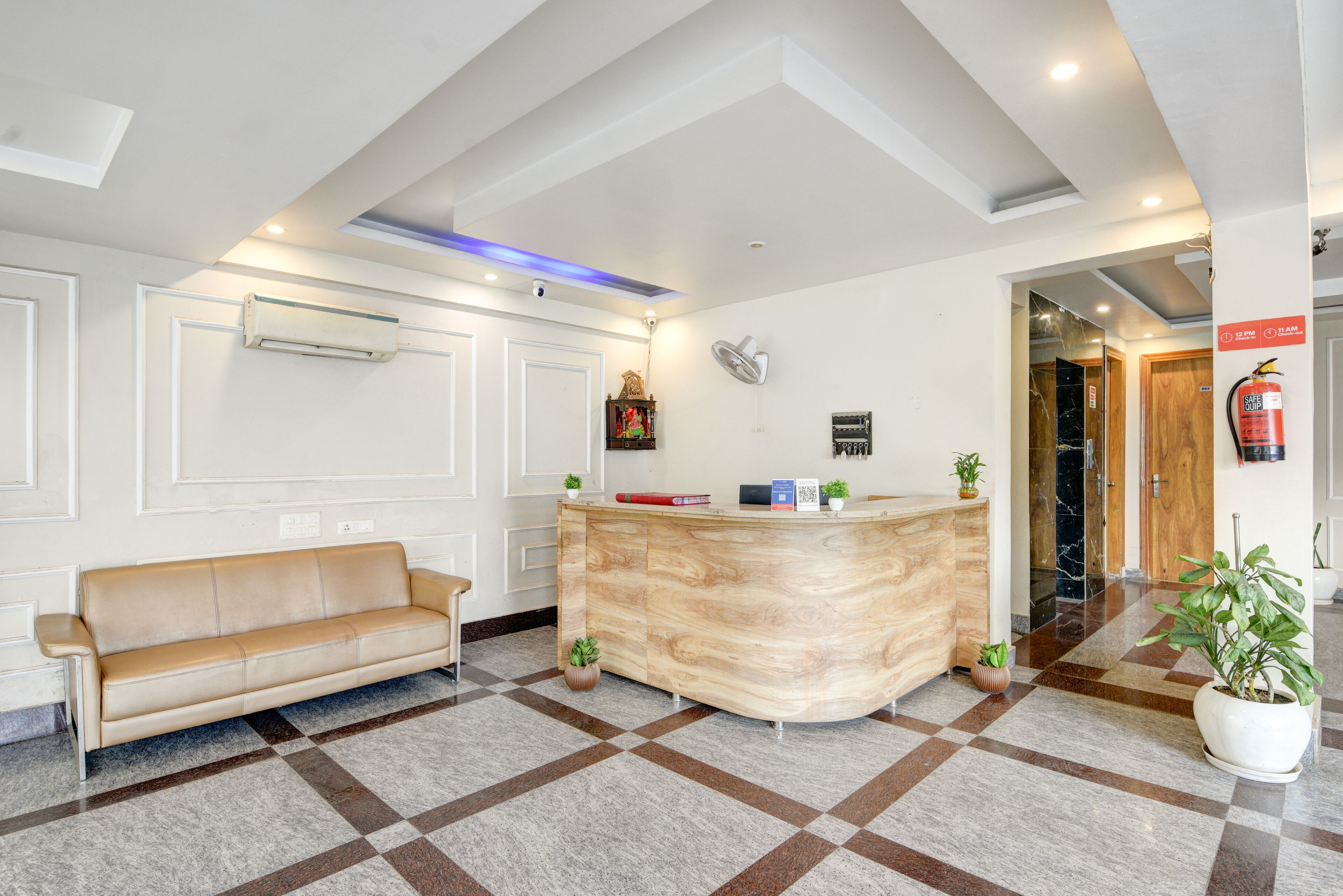 Un área de recepción con un mostrador de madera, un sofá color crema y un piso a cuadros.