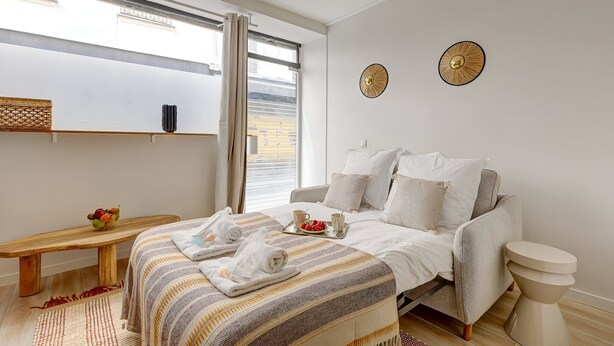 Et hotelværelse med en seng, en bænk, et lille bord med frugt og to billeder på væggen.