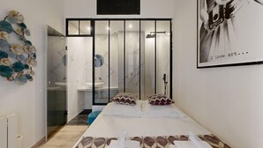 Une chambre d’hôtel moderne dotée d’un grand lit, d’une douche en verre et d’un élément décoratif mural.