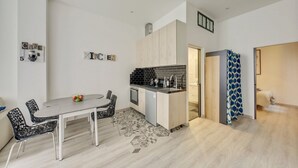 Une cuisine moderne avec un coin repas, comprenant un îlot central, un dosseret carrelé en noir et blanc et un sol à motifs.