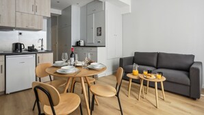 Una cocina moderna con electrodomésticos Bosch, un comedor con mesa redonda y sillas, y un sofá gris en la sala de estar.