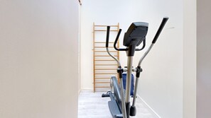 A narrow hallway with a wooden ladder and exercise equipment, including an elliptical machine and a stationary bike. - TBS 6 - Beautiful apartment near Opéra Garnier (Paris)