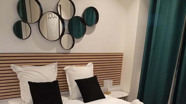 A neatly made bed with white linens, black and white pillows, and a beige throw blanket. - TheBlueStay 27 - Charming and elegant studio (Paris)