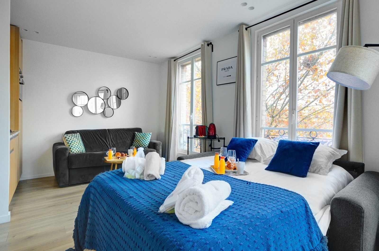 A hotel room with a large bed, a sofa, a coffee table, and a wall-mounted mirror.