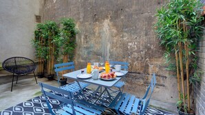 A small outdoor dining area with a table set for two, surrounded by bamboo plants and blue metal chairs. - TBS 29 - Elegant apartment with terrace (Paris)