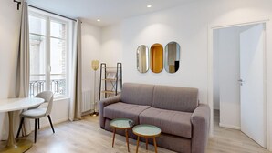 A living room with a sofa, two side tables, a floor lamp, and a dining table. - TBS 29 - Elegant apartment with terrace (Paris)