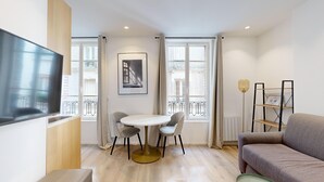 A modern living room with a round table, two chairs, a sofa, a TV, and a framed picture on the wall. - TBS 29 - Elegant apartment with terrace (Paris)