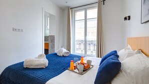 A hotel room with a bed, a tray with breakfast items, a window with curtains, and a balcony view. - Bluestay 33 - Charming apartment in Paris (Paris)