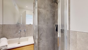 Une salle de bain moderne avec une douche à parois de verre, un lavabo blanc et un miroir.