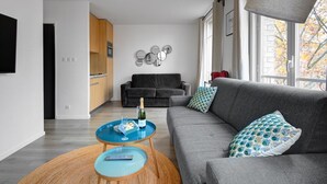 A modern living room with a grey sofa, a round coffee table, and a television on the wall. - TBS 35 - Cosy and refined apartment (Paris)