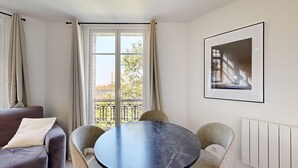 A room with a round table, two chairs, a sofa, and a window with curtains. - TBS 35 - Cosy and refined apartment (Paris)