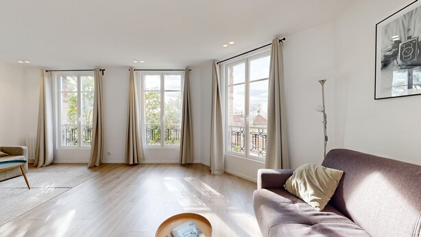 A spacious living room with large windows, a sofa, a coffee table, and a floor lamp. - TBS 38 - Cosy and elegant duplex apartment (Paris)