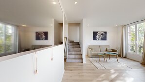 A modern interior with a staircase, a sofa, and two framed pictures on the walls. - TBS 38 - Cosy and elegant duplex apartment (Paris)