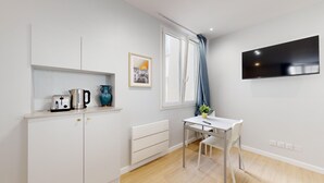 A compact living space with a kitchenette, a dining area, and a TV mounted on the wall. - TBS 196 - Charming apartment in the Marais (Paris)