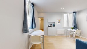 A modern, well-lit room with a dining area, a small kitchen, and a seating area. - TBS 196 - Charming apartment in the Marais (Paris)