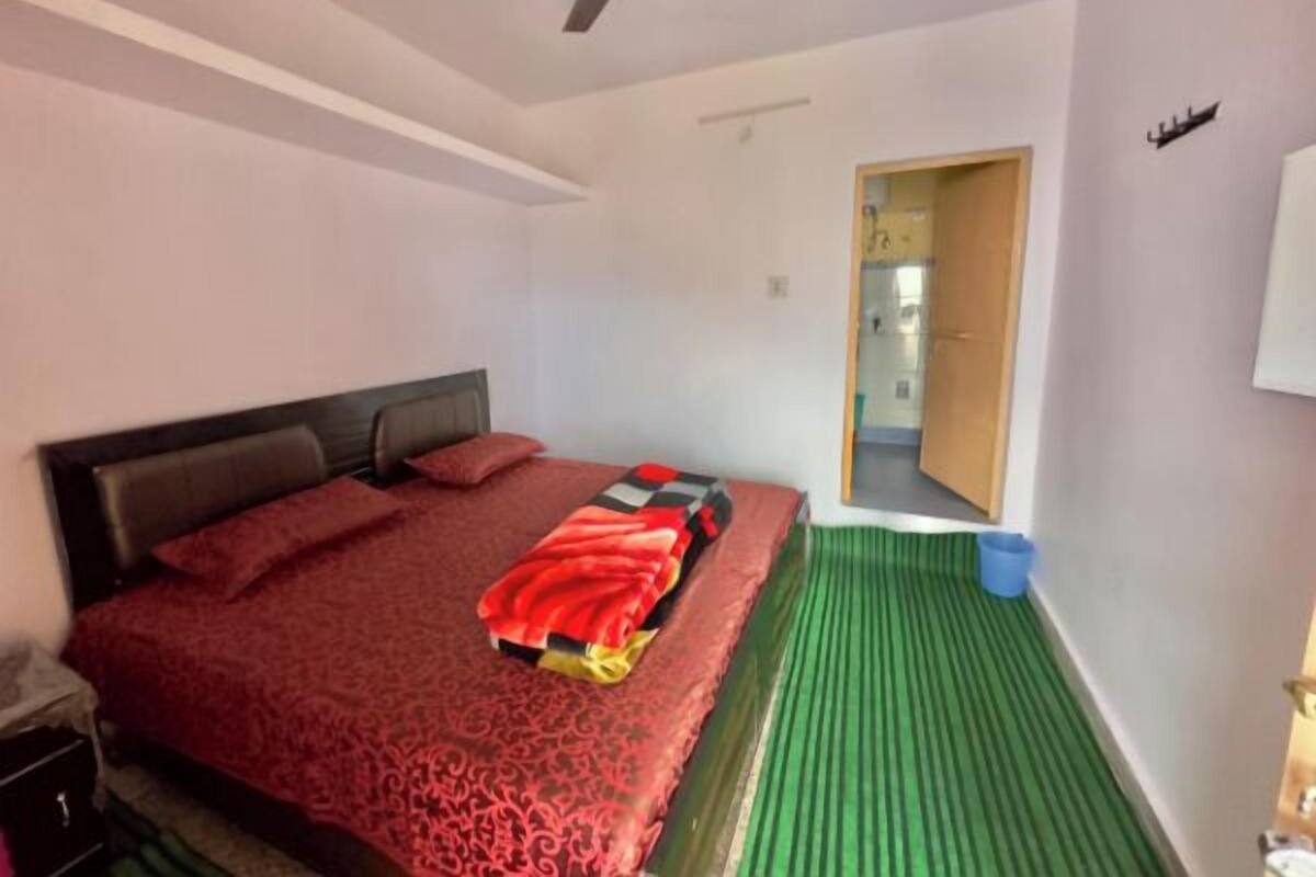 A bedroom with a bed, a ceiling fan, a door, and a green mat.