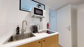 Eine moderne Küche mit Spüle aus Edelstahl, einer Mikrowelle, einem Wasserkocher und einer Kaffeemaschine.