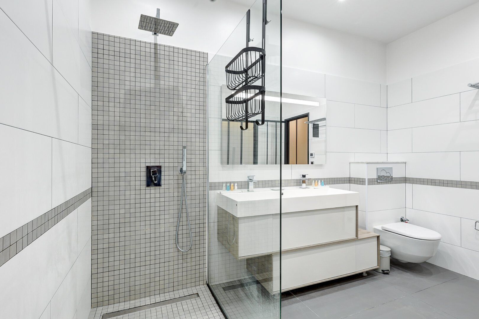 A modern bathroom with a glass shower enclosure, a vanity with a mirror, and a toilet.