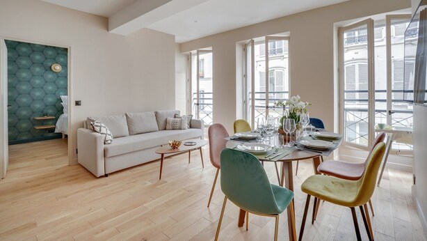 Ein modernes Wohnzimmer mit Sofa, einem Esstisch für vier Personen und einem Balkon mit Blick.
