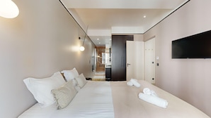 Ein modernes Hotelzimmer mit einem großen Bett, einem flachbildfernseher an der Wand und einem begehbaren Kleiderschrank.