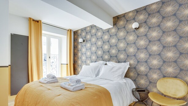 A hotel room with a bed, a chair, and a wall with a geometric pattern. - TBS 43 - Sumptuous apartment in the heart of Paris (Paris)