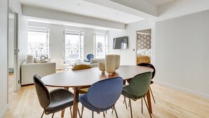 A modern dining area with a round table, six chairs, and a TV mounted on the wall. - TBS 43 - Sumptuous apartment in the heart of Paris (Paris)