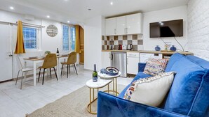 A compact living space with a dining area, kitchenette, and a TV mounted on the wall.