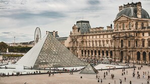 Une vaste place ouverte, avec la pyramide du Louvre et le bâtiment principal du musée du Louvre en arrière-plan.