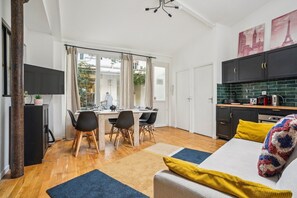 A compact living space with a dining area, kitchenette, and a bed with colorful bedding. - TBS 160 - Modern and elegant haven of peace (Paris 10 Entrepôt)