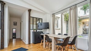 Ein moderner Essbereich mit Holztisch und Stühlen, einem Fernseher und Blick auf die Stadt durch große Fenster.