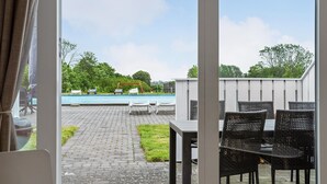 Un patio al aire libre con piscina, sillas de descanso y una mesa.