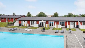 Un hotel con piscina, zona de estar al aire libre y fachada de color rojo.