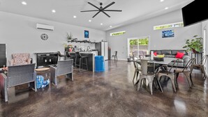 Amplia sala de estar con mesa de comedor, sillas, sofá y zona de cocina con barra.