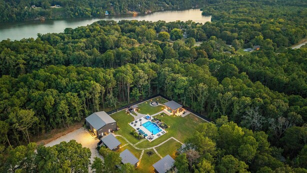 Vista aérea de una propiedad con piscina, varios edificios y un lago.