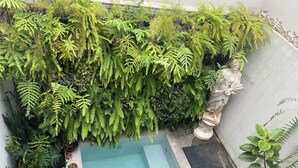Ein kleiner Gartenbereich mit verschiedenen Kübelpflanzen und einer Statue.