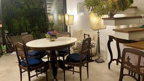 Ein Essbereich mit einem runden Tisch, sechs Stühlen, einer Chandelüstere und einer Treppe mit Holzdielen.